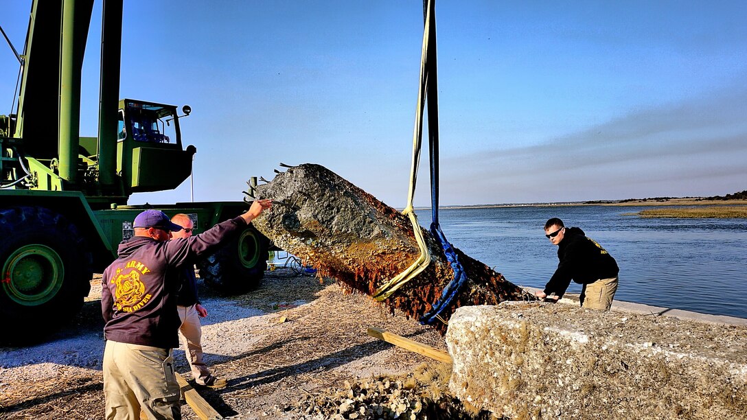 Soldiers from the 511th Engineer Dive Detachment prepare to remove slings from a concrete piling being removed from the water. The active duty unit removed a dozen 10,000 pound pilings at the reserve center as part of a Troop Construction project, saving the Army money while performing real world training.