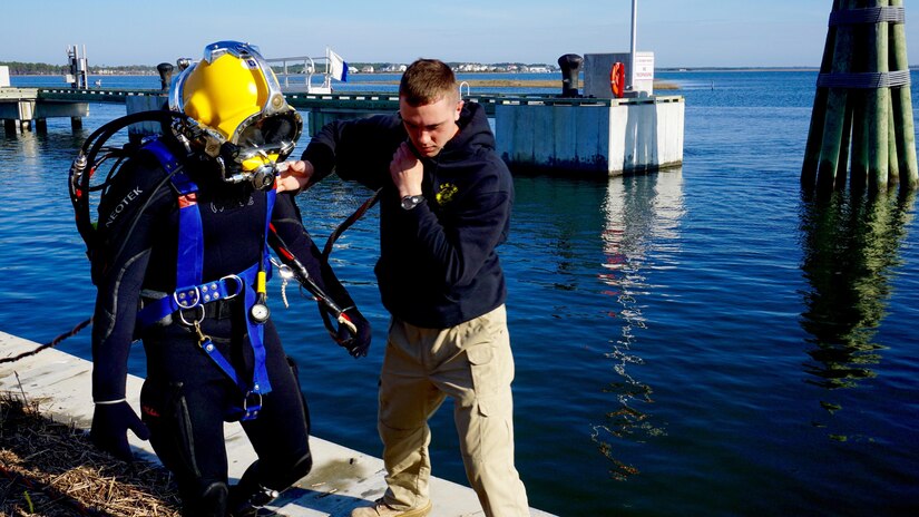 Pfc. Michael Pate from the 511th Engineer Dive Detachment assists Spc. Michael Higgonbotham to the pier for Bradley’s dive to perform an underwater cutting mission at the Morehead City, N.C., Reserve Center pier. The active duty unit removed a dozen 10, 000 pound pilings at the reserve center as part of a Troop Construction project, saving the Army money while performing real world training.