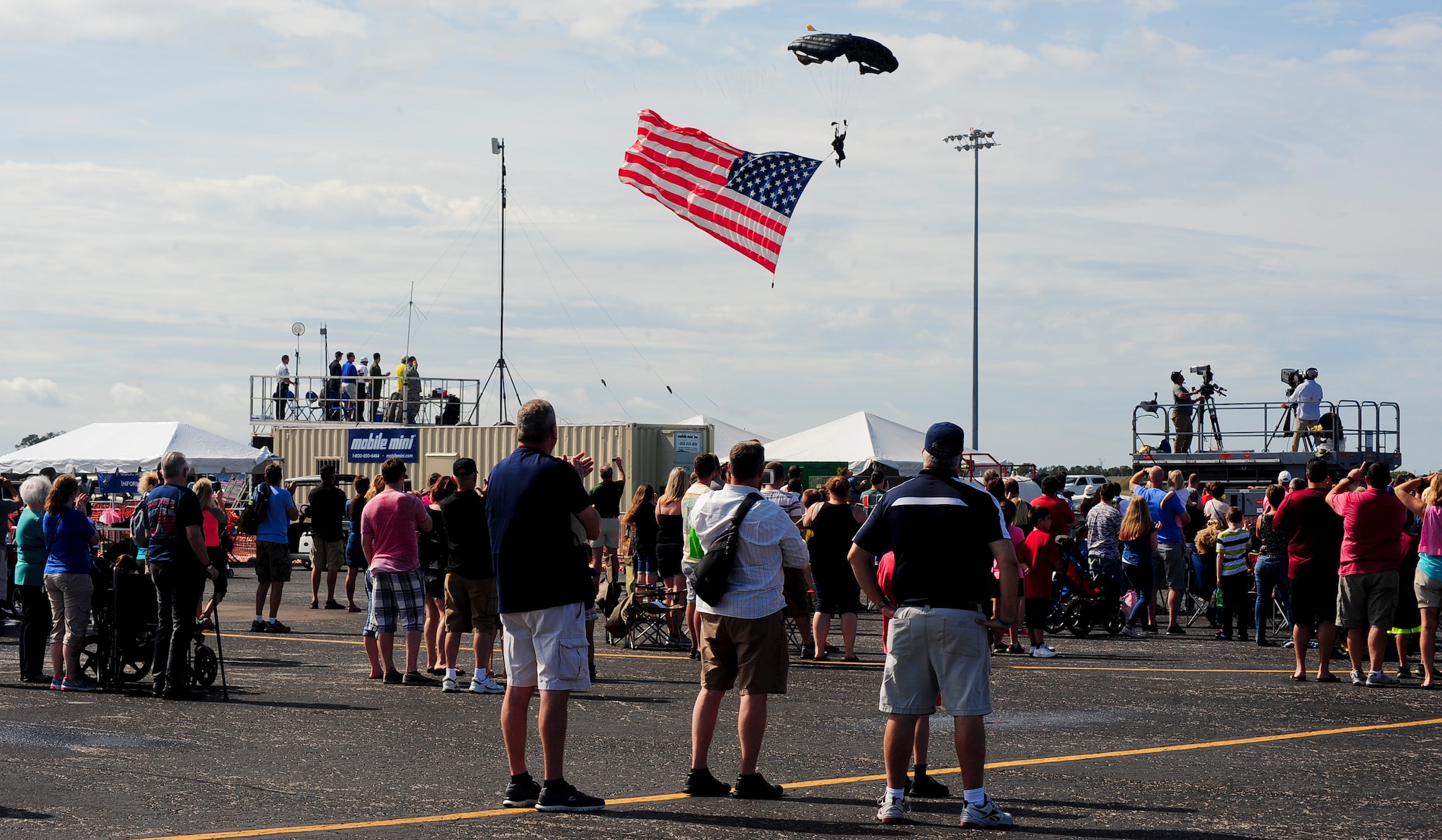 Spectators watch as a member of the United States Special Operations Command (USSOCOM) Parachute Team displays the flag during the National Anthem during Tampa Bay AirFest 2016 at MacDill Air Force Base, Fla., March 20, 2016. The Para-Commandos perform precision free fall parachute demonstrations across the United States, informing the public about the USSOCOM mission. (U.S. Air Force photo by Senior Airman Jenay Randolph)