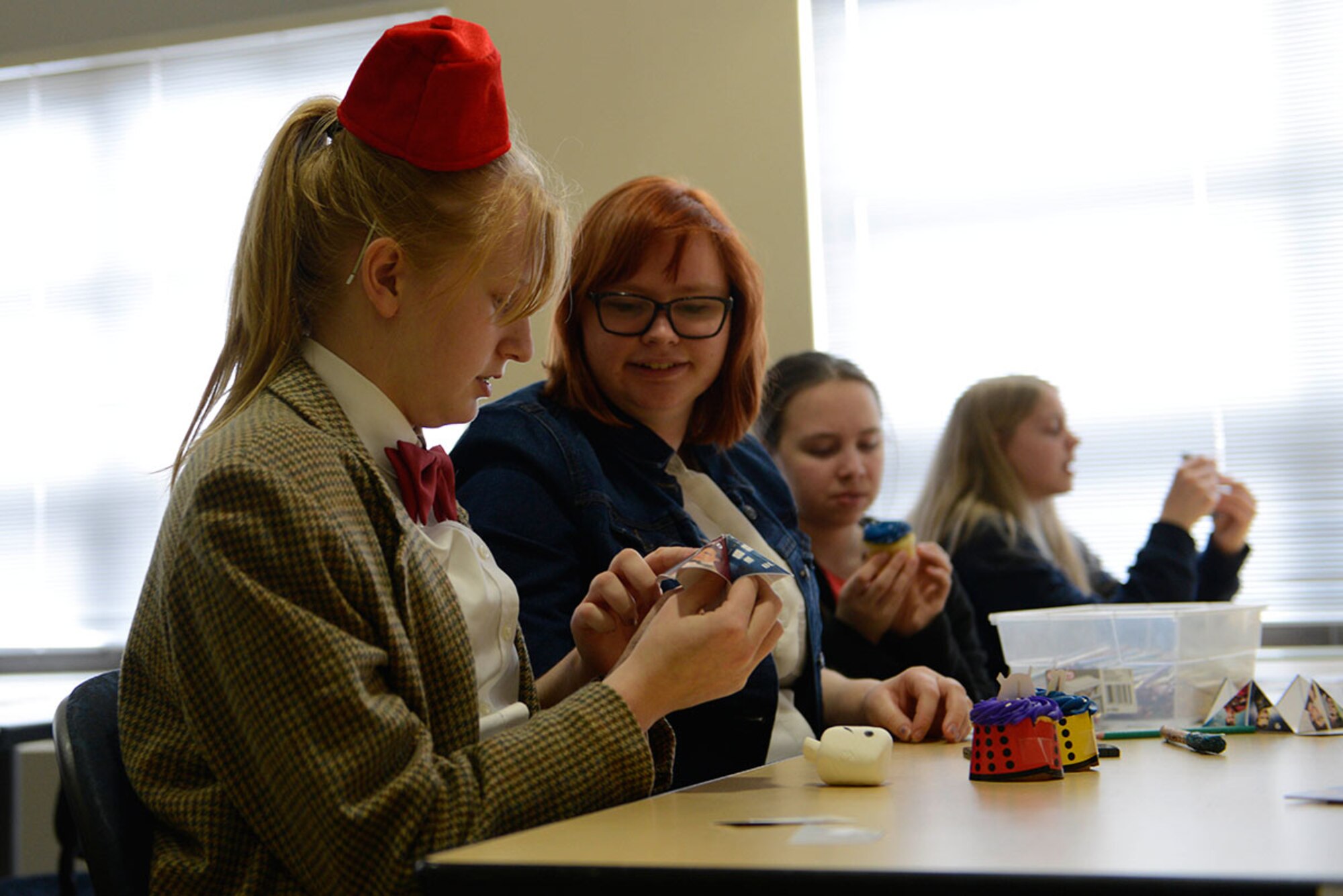Teenagers fold paper fortune tellers during the Dr. Who Wibbly Wobbly Timey Wimey teen program at the Joint Base Elmendorf- Richardson Library, March 16, 2016. In addition to dressing in Dr. Who costumes, teens played games and made multiple crafts to take home. (U.S Air Force photo by Airman Valerie Monroy)