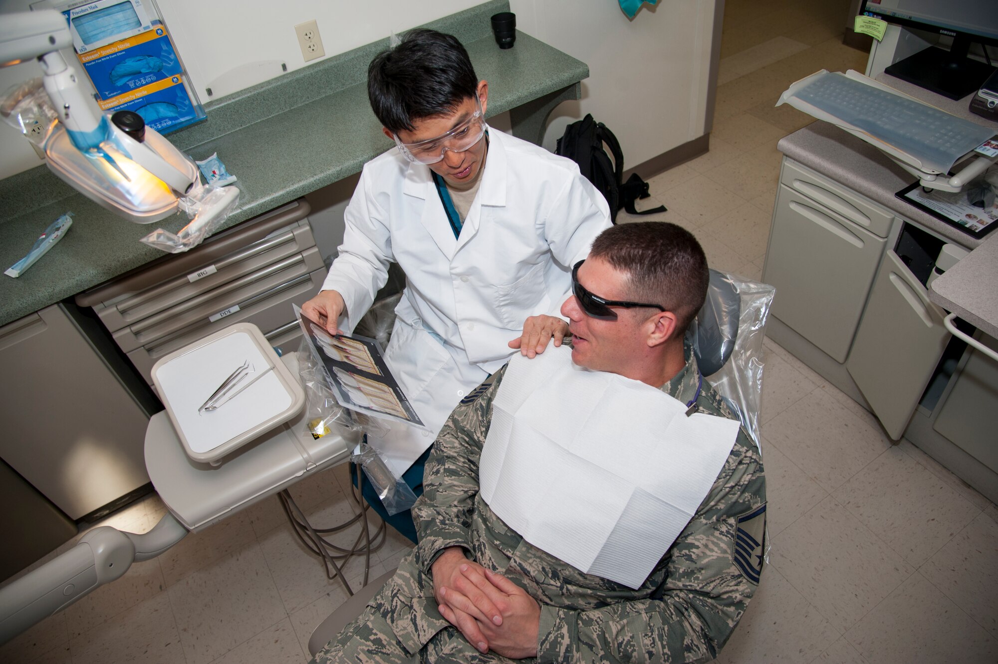 PETERSON AIR FORCE BASE, Colo. - Lt. Col. Brett M. Chung, Peterson Dental Clinic professional services chief, explains to a patient the benefits of proper oral hygiene at the dental clinic here March 22, 2016. Chung first came to the U.S. as a 17-year-old high school student attending classes in Centerberg, Ohio. (U.S. Air Force photo by Airman 1st Class Dennis Hoffman)