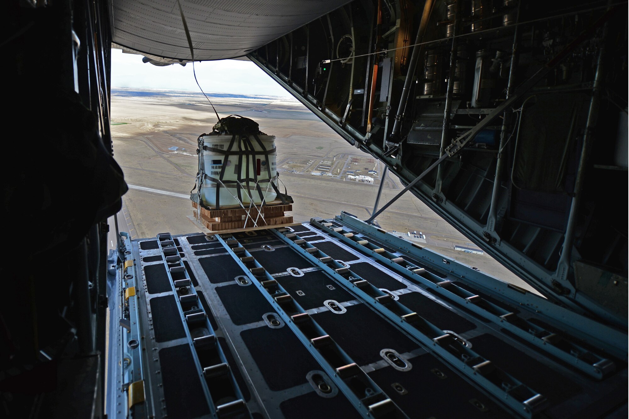 A High Velocity Container Delivery System, or HVCDS, bundle is dropped from a Montana Air National Guard C-130 on the flight line at Malmstrom Air Force Base, Mont., March 5, 2016. This is the first time the MANG unit has dropped shipments of this size on Malmstrom’s flight line, also known as Charging Charlie. (U.S. Air Force photo/Tech. Sgt. Patrick Mitchell)
