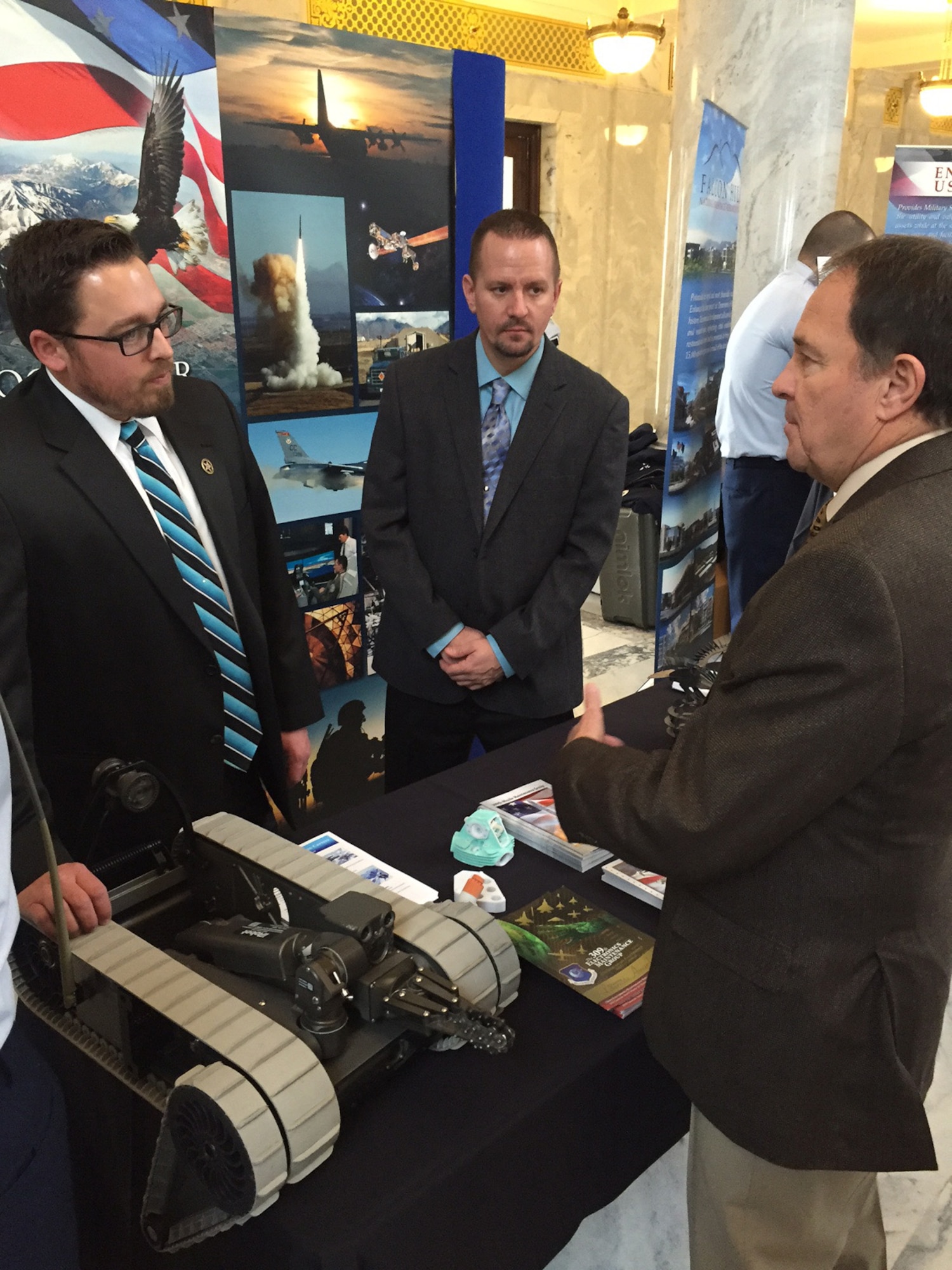 Lane Farka, (left), and Christian Cross, Ogden Air Logistics Complex Strategy and Business Development Team members, meet with Utah Governor, Gary Herbert, Feb. 5 at the Utah State Capitol. The Meet the Military event gave Utah military organizations the opportunity to showcase their capabilities to Utah state legislators and other state senior leaders. (U.S. Air Force photo by Scott Hayes)