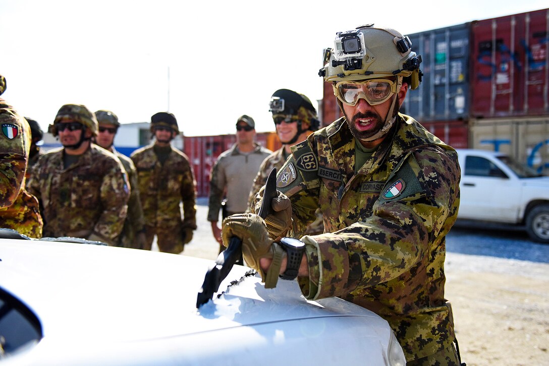 An Italian soldier uses a cutting tool on the end of a crash ax to cut away a truck’s hood during combined extrication training at Bagram Airfield, Afghanistan, March 19, 2016. The Italian soldiers traveled from their base in Herat, Afghanistan, to work with the Air Force pararescuemen and learn tactics for rescuing people from vehicles. Air Force photo by Capt. Bryan Bouchard
