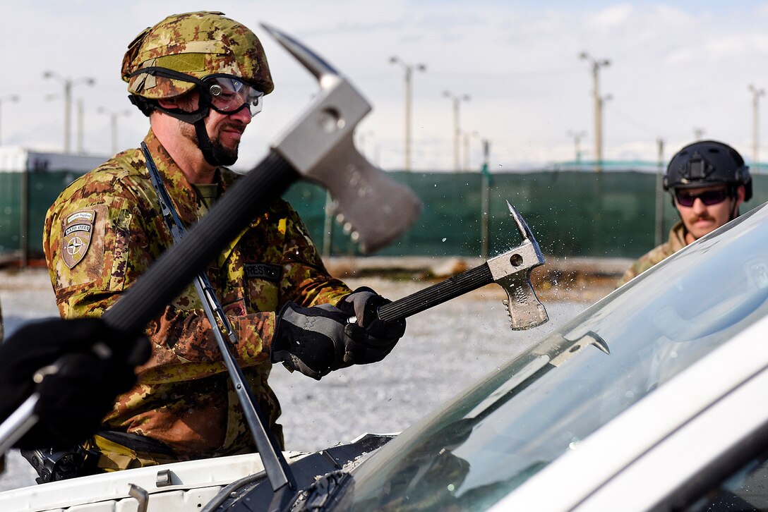 Italian soldiers use crash axes to cut away a vehicle’s windshield during combined extrication training with U.S. airmen at Bagram Airfield, Afghanistan, March 19, 2016. Air Force photo by Capt. Bryan Bouchard