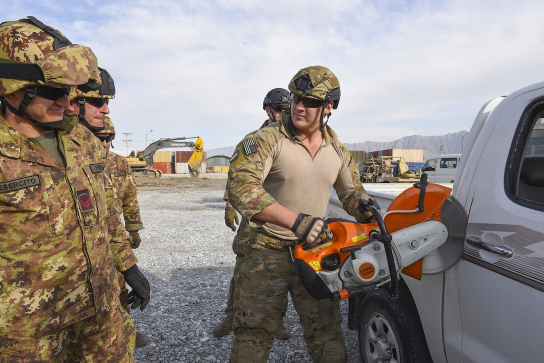 A U.S. airman demonstrates how to use a fire rescue saw to cut through a vehicle door during combined extrication training with Italian soldiers at Bagram Airfield, Afghanistan, March 19, 2016. Air Force photo by Capt. Bryan Bouchard