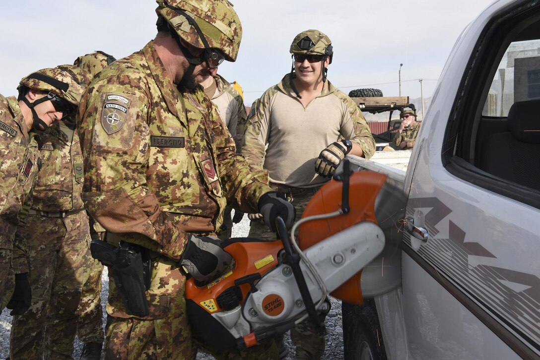An Italian soldier uses a fire rescue saw to remove a truck door during extrication training with U.S. airmen at Bagram Airfield, Afghanistan, March 19, 2016. Air Force photo by Capt. Bryan Bouchard