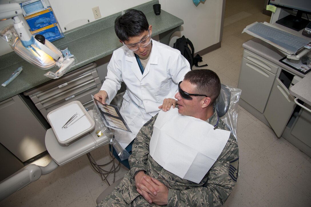 Lt. Col. Brett Chung, the professional services chief at the dental clinic on Peterson Air Force Base, Colo., explains to a patient the benefits of proper oral hygiene March 22, 2016. Chung first came to the U.S. as a 17-year-old high school student attending classes in Centerberg, Ohio. (U.S. Air Force photo/Airman 1st Class Dennis Hoffman)