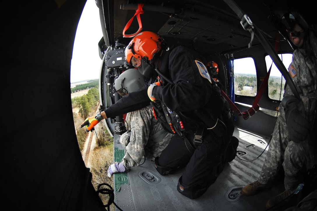 A member of the South Carolina Helicopter Aquatic Rescue Team, foreground, and a soldier point out a simulated casualty while participating in a medevac training and certification mission in Eastover, S.C., March 9, 2016. South Carolina Army National Guard photo by Staff Sgt. Roberto Di Giovine
