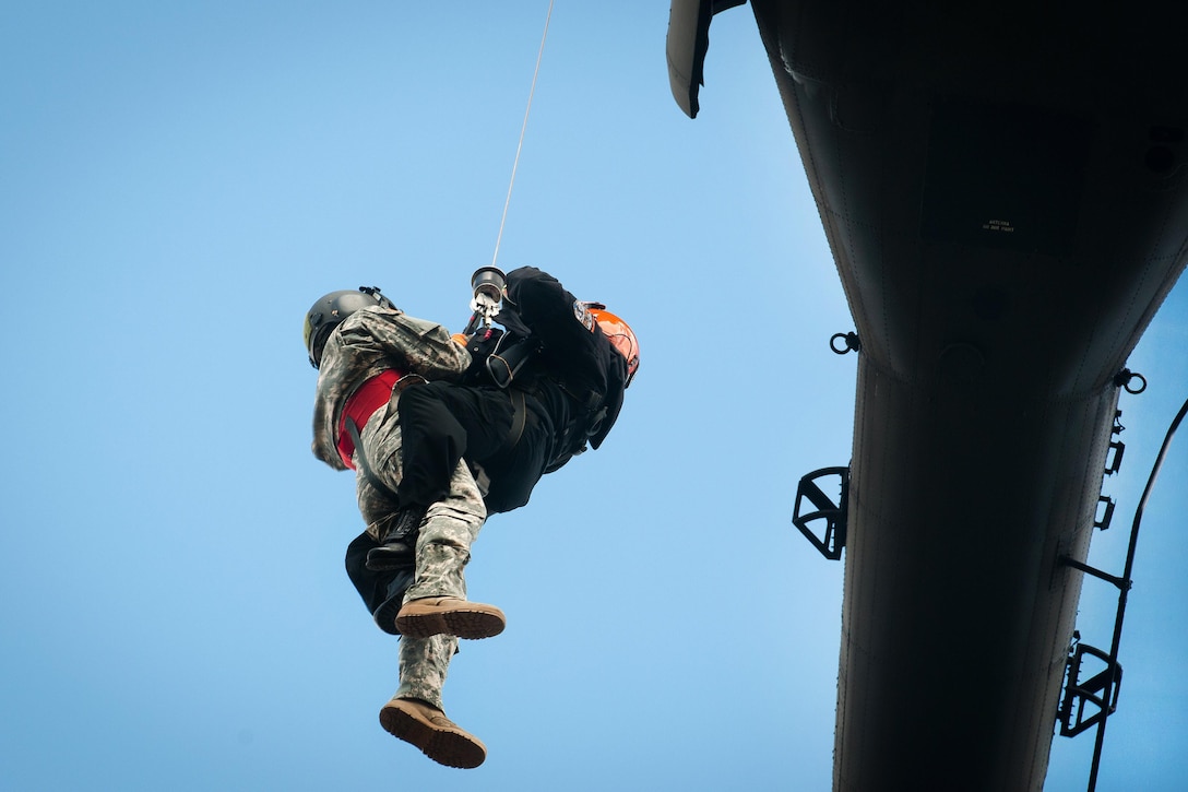 A soldier helps a member of the South Carolina Helicopter Aquatic Rescue Team get hoisted up to a UH-60 Black Hawk helicopter during a medevac training and certification mission in Eastover, S.C., March 9, 2016. South Carolina Army National Guard photo by Staff Sgt. Roberto Di Giovine
