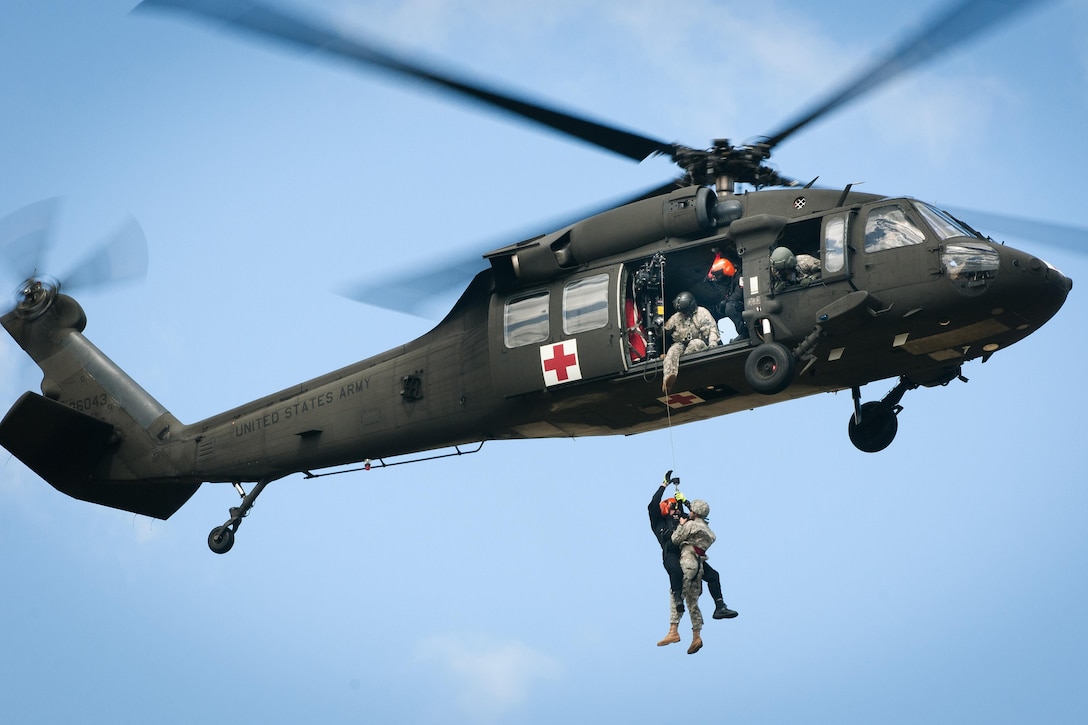 A soldier helps a member of the South Carolina Helicopter Aquatic Rescue Team being hoisted into a UH-60 Black Hawk helicopter during a medevac training and certification mission in Eastover, S.C., March 9, 2016. South Carolina Army National Guard photo by Staff Sgt. Roberto Di Giovine