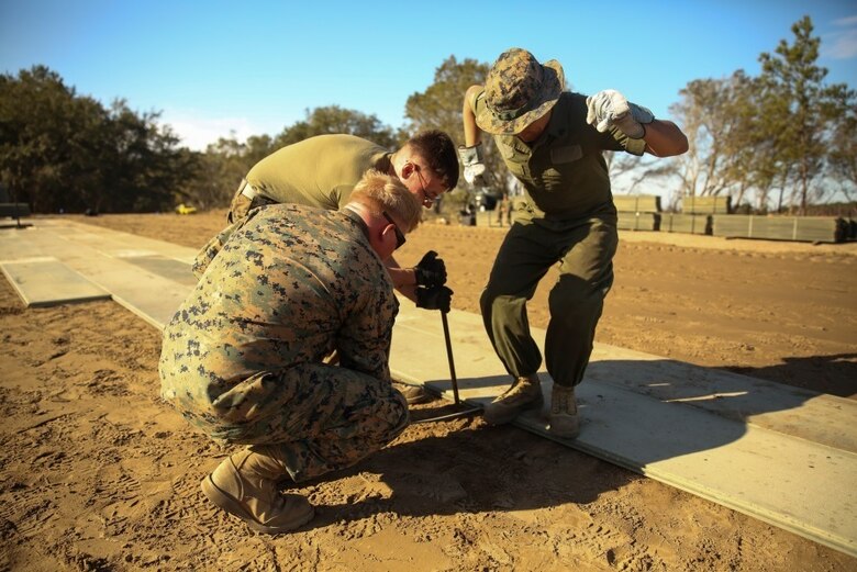 U.S. Marines with Marine Wing Support Squadron 272 construct a vertical take-off and landing pad during a Marine Corps Combat Readiness Evaluation at Marine Corps Auxiliary Landing Field Bogue, N.C., March 17, 2016. The MCCRE, which went from March 14-18, tested MWSS-272’s ability to build an AM-2 aluminum matting V/TOL pad ready to accept incoming aircraft. MWSS-272 is part of Marine Aircraft Group 26, 2nd Marine Aircraft Wing. (U.S. Marine Corps photo by Cpl. Kaitlyn V. Klein/Released)
