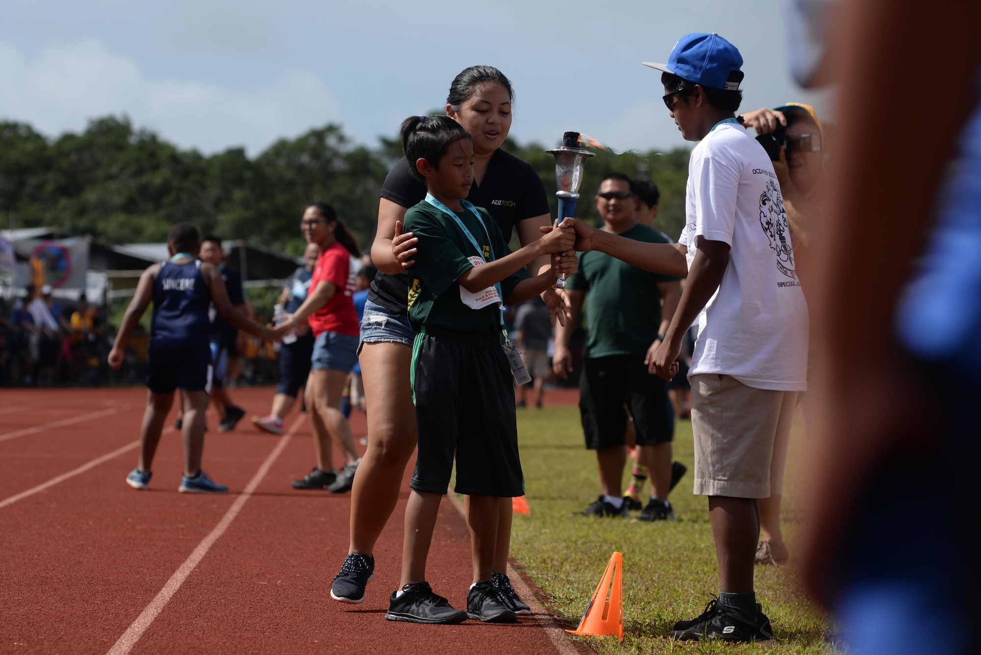 Athletes participating in the 2016 Special Olympics Guam Track and Field Competition pass on the torch during a relay of the torch March 19, 2016, at Okkodo High School in Dededo, Guam. The relay of the flame is traditionally used to signal the beginning of the Olympics and to send a message of peace and friendship. (U.S. Air Force photo/Airman 1st Class Jacob Skovo)