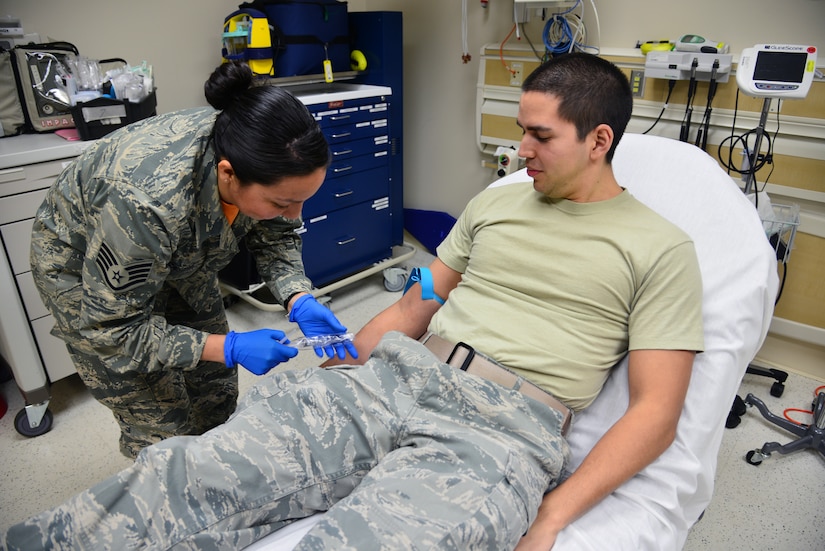 U.S. Air Force Staff Sgt. Christine Castro, the ambulance service noncommissioned officer in charge at the 633rd Medical Operations Squadron, opens a syringe prior to beginning an IV on Senior Airman Bryan Almonacid, an aerospace medical service technician from the 633rd MDOS, in the USAF Hospital Langley Emergency Room at Langley Air Force Base, Va., Feb. 26, 2016. The Langley ER staff includes nurses, doctors, medical technicians, civilian employees, contractors and paramedics who work around the clock to treat Department of Defense beneficiaries. (U.S. Air Force photo by Staff Sgt. Aubrey White)