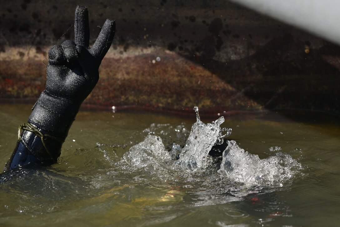 U.S. Army Sgt. Gordon Yeaple, a salvage diver and noncommissioned officer in charge with the 569th Engineer Dive Detachment, signals to the safety and stand-by divers that he is going down at Fort Eustis, Va., March 18, 2016. The divers use hand signals and rope-line pulls to communicate their status and needs as verbal communication is not possible during a dive. (U.S. Air Force photo by Staff Sgt. Natasha Stannard)