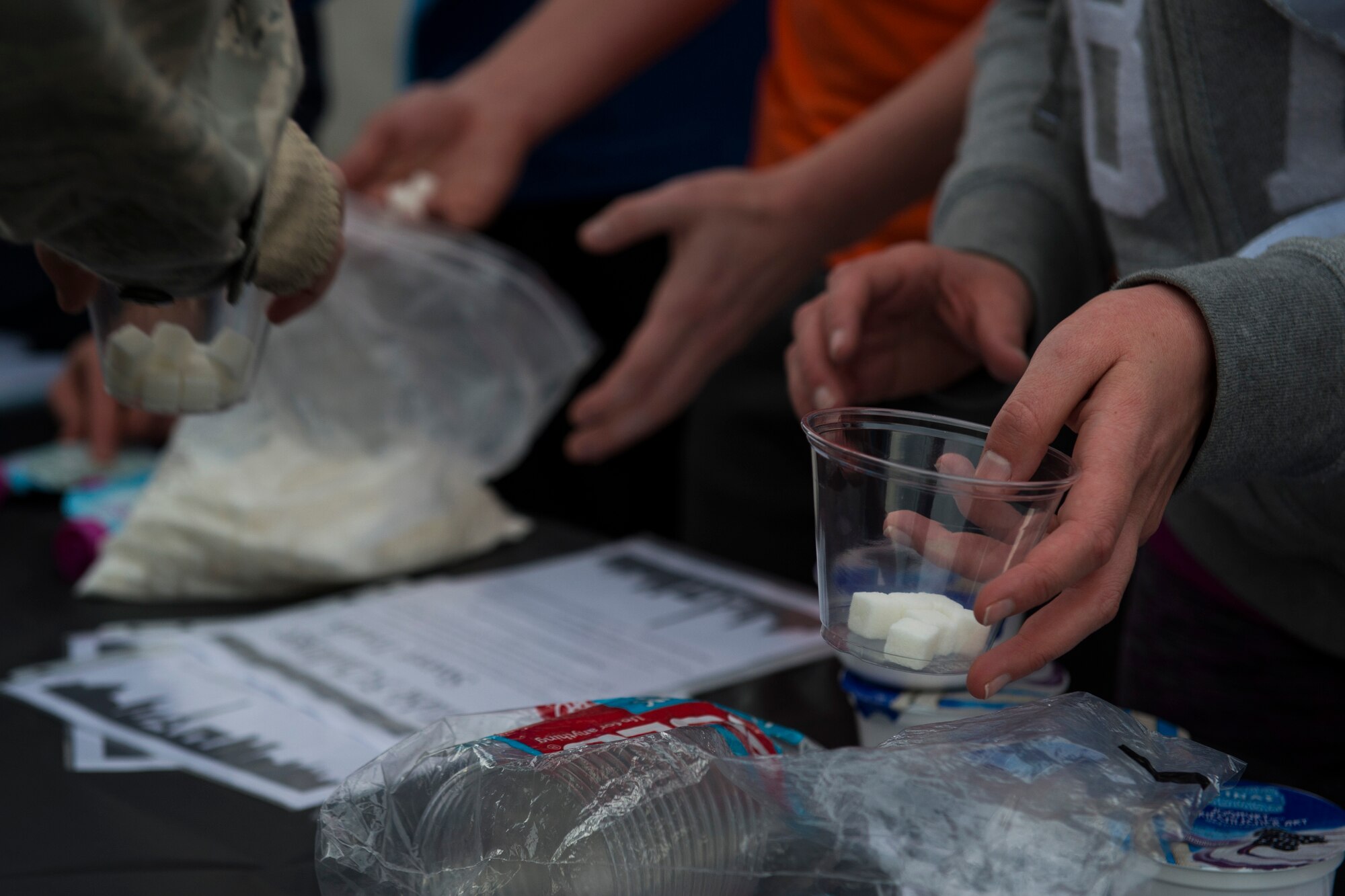 Participants place sugar cubes in cups at a station challenge during the Amazing Nutrition 5k Challenge at Spangdahlem Air Base, Germany, Mar. 22, 2016. Teams needed to match the exact amount of sugar cubes with the sugar of a certain food item by correctly reading the nutritional facts. (U.S. Air Force photo by Senior Airman Luke Kitterman/Released)