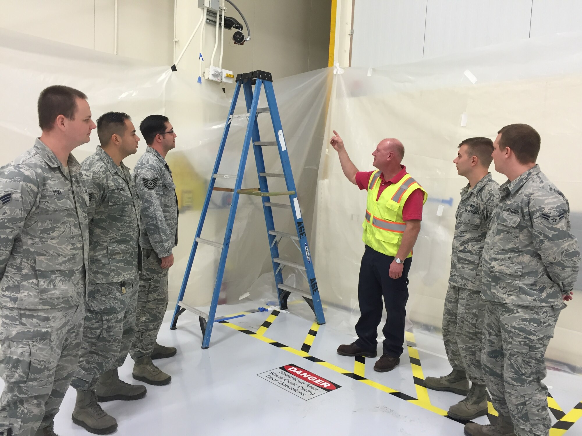 A fire protection engineer trains fire alarm shop staff at Nellis Air Force Base, Nevada, on a newly installed flame detection system during acceptance testing of a hangar addition. (Air Force photo/Susan Lawson/Released)



