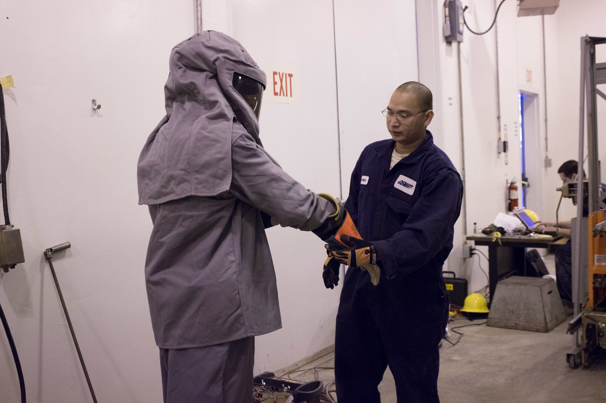 The Staff Sgt. Allan Flores, Air Force Civil Engineer Center Civil Engineer Maintenance Inspection and Repair Team technician, helps 30th Civil Engineer Squadron Electrician Senior Airman Cubby Fowler don personal protective equipment Level 4 to support the 30th Civil Engineer Squadron's bi-annual maintenance effort.  The PPE is capable of withstanding an electrical arc-flash of 50 calories per square centimeter, and it is the highest level of PPE required anywhere on Vandenberg’s 300-mile distribution grid.(U.S. Air Force Photo/Susan Lawson/Released)