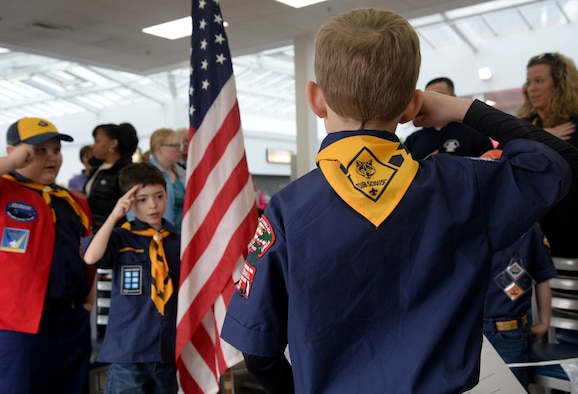 RAF Mildenhall Cub Scout Pack 215 and their families pay respects to the flag during the posting of the colors at the Pinewook Derby March 19, 2016, on RAF Mildenhall, England. The scouts entered their handmade pinewood race cars in a tournament to determine whose racer was the fastest. The race was organized to put the winners of each heat head-to-head in the championships. (U.S. Air Force photo by Senior Airman Justine Rho/Released)