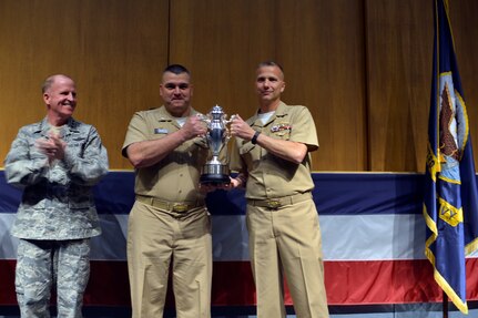 U.S. Navy Cmdr. Kenneth M. Curtin Jr., commanding officer of USS Wyoming Gold Crew (right), and U.S. Navy Cmdr. Wayne C. Wall, commanding officer of USS Wyoming Blue Crew (center), hold up an Omaha Trophy during an award ceremony honoring the USS Wyoming (SSBN 742) at Naval Submarine Base Kings Bay, Ga., March 23, 2016. During the ceremony, U.S. Air Force Lt. Gen. Stephen W. Wilson, U.S. Strategic Command (USSTRATCOM) deputy commander (left), and Mr. Tom Janssen, Strategic Command Consultation (SCC) Committee representative (not pictured), presented the 2015 Omaha Trophy, ballistic missile submarine category, to Curtin and Wall in recognition of the USS Wyomingâ€™s contributions to USSTRATCOM's global strategic missions. The Omaha Trophy, which dates back to the U.S. Air Force's Strategic Air Command, was originally created by the SCC in 1971. At the time, a single trophy was presented annually as a token of appreciation to USSTRATCOM's best wing. Since then, the tradition has evolved to unit-level awards that recognize the command's premier intercontinental ballistic missile (ICBM) wing, ballistic missile submarine, strategic bomber wing and global operations (space/cyberspace) unit. This year, a new category was added to include the combatant command's top strategic aircraft wing. (U.S. Navy photo courtesy of Commander, Submarine Group Ten\r\nPublic Affairs) Story Available: https://www.stratcom.mil/news/2016/595/-/