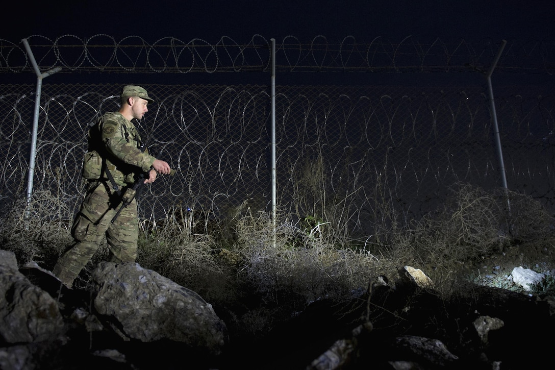 Air Force Airman 1st Class Aaron Orvedahl checks the security along a fence line during a walking patrol at Bagram Airfield, Afghanistan, March 23, 2016. Orvedahl is assigned to the 455th Expeditionary Security Forces Squadron Flightline Security Quick Reaction Force team. Air Force photo by Tech. Sgt. Robert Cloys