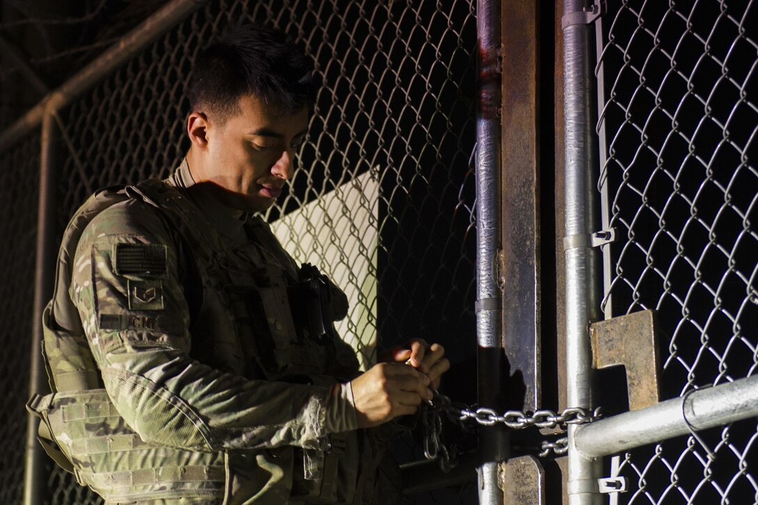 Air Force Staff Sgt. Rodrigo Cid removes the lock from a gate during a walking patrol at Bagram Airfield, Afghanistan, March 23, 2016. Air Force photo by Tech. Sgt. Robert Cloys