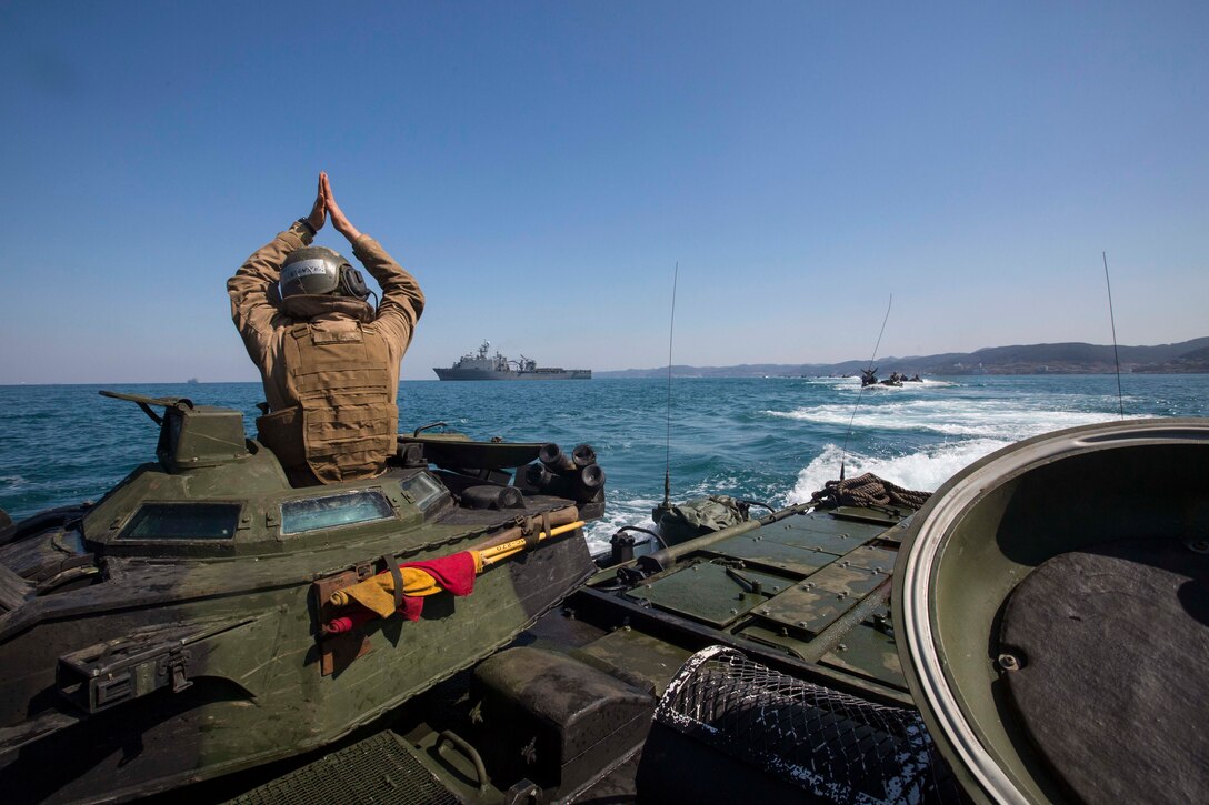 U.S. Marine Cpl. Christopher Lee, with Alpha Company, Battalion Landing Team 1st Battalion, 5th Marines, 31st Marine Expeditionary Unit, uses hand signals to communicate with other AAV-P7/A1 Amphibious Assault Vehicles while conducting a combined amphibious assault on Dogu Beach, South Korea, as part of Ssang Yong 16, March 12, 2016. Ssang Yong is a biennial combined amphibious exercise conducted by U.S. forces with the Republic of Korea Navy and Marine Corps, Australian Army and Royal New Zealand Army forces in order to strengthen interoperability and working relationships across a wide range of military operations. The Marines and sailors of the 31st MEU are in Korea as part of their spring deployment to the Asia-Pacific region. Lee, a native of Haslet, Texas, is a crew chief with Alpha Co., BLT 1/5,31st MEU. (U.S. Marine Corps photo by Lance Cpl. Carl King Jr./Released)