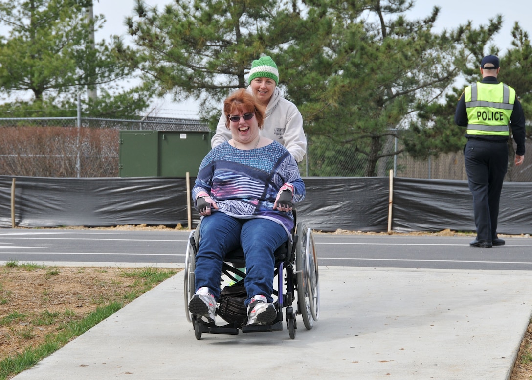 Laura Cox with Defense Logistics Agency Installation Support assists Vivian d’Aleio, also with DLA Installation Support, as the pair takes part in the Spring Fling 5K at Fort Belvoir, Virginia, March 20.