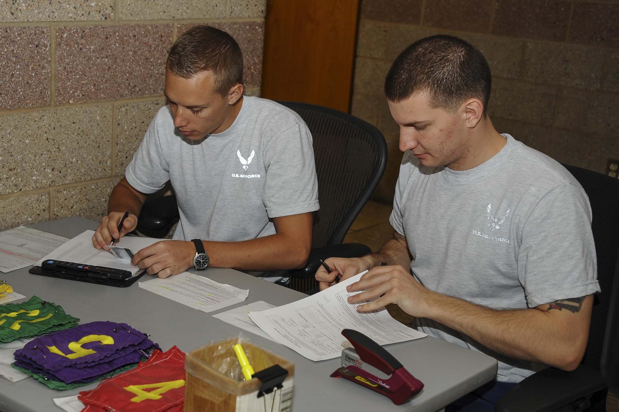 U.S. Air Force Airman 1st Class Joshua Dittman and Airman 1st Class Brendon Davis, acting 355th Force Support Squadron fitness assessment cell augmentees, review an AF Form 4446 and 36-2905 Fitness Screening Questionnaire before a fitness assessment at Davis-Monthan Air Force Base, Ariz., Feb. 24, 2016. . The D-M fitness assessment cell, which administers the fitness assessments, is in the process of transitioning all physical paperwork to digital copies to save time and resources.  (U.S. Air Force photo by Airman 1st Class Mya M. Crosby/Released)