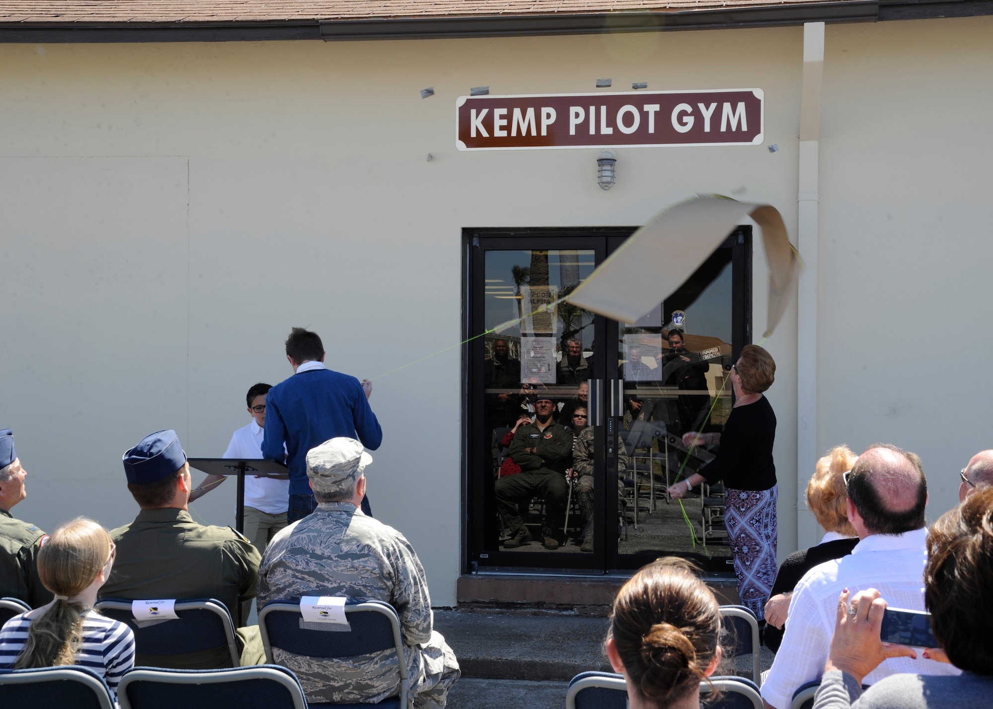 Adelina Kemp, unveils the sign of the newly named Kemp Pilot Gym March 21, at Tyndall, Air Force Base, Fla. The purpose of this event was to dedicate the gym to the memory of Col. Larry “Pinball” Kemp. (U.S. Air Force photo by Senior Airman Solomon Cook/Released)