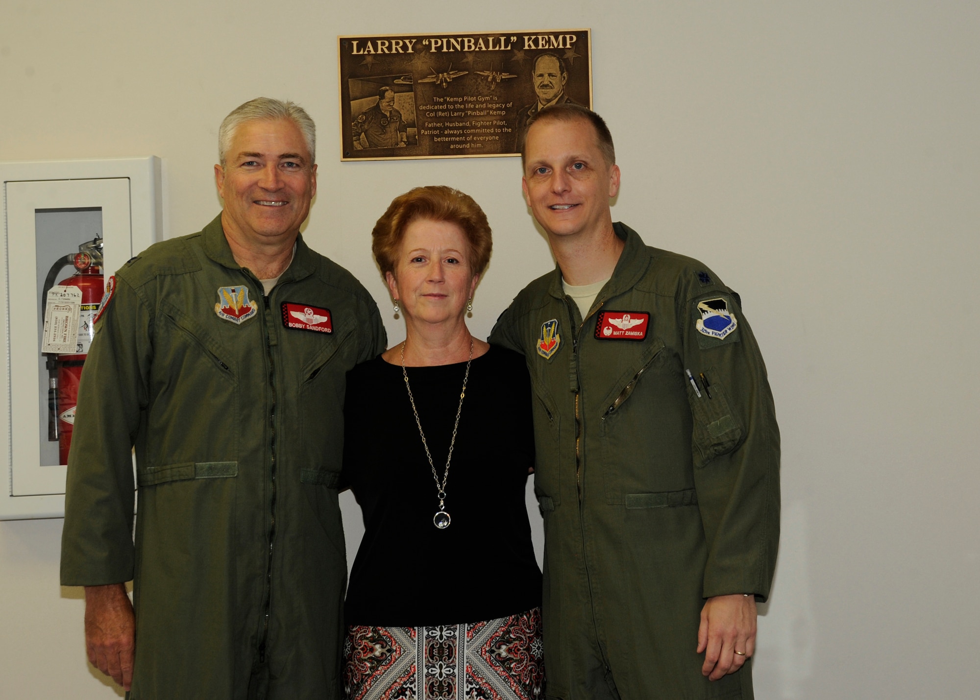 From left to right: Colonel Robert Sanford, 601st Air Operations Center combat control officer, Ms. Adelina Kemp, wife of Col. Larry “Pinball” Kemp, and Lt. Col. Matthew Zamiska, 325th Training Support Squadron commander, pose for a photo March 21, at the newly named Kemp Pilot Gym at Tyndall, Air Force Base, Fla. The event commemorated the pilot’s gym in memory of Col. Larry “Pinball” Kemp. (U.S. Air Force photo by Senior Airman Solomon Cook/Released)