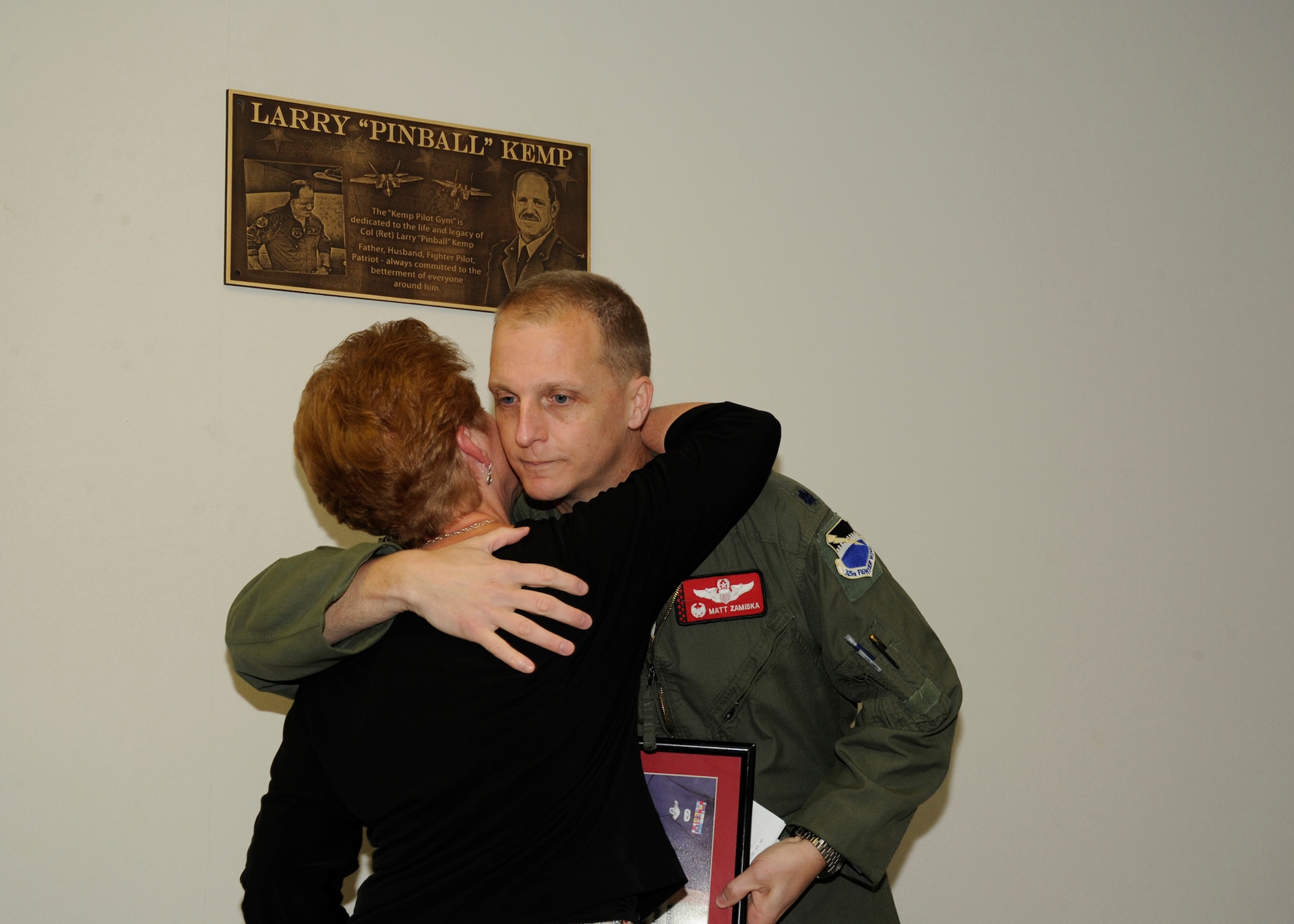 Adelina Kemp, (left) hugs Lt. Col. Matthew Zamiska, 325th Training Support Squadron commander, after being presented a lithograph of Col. Larry “Pinball” Kemp by March 21, at the newly named Kemp Pilot Gym. The gym was renamed to honor the memory Col. Kemp. (U.S. Air Force photo by Senior Airman Solomon Cook/Released)