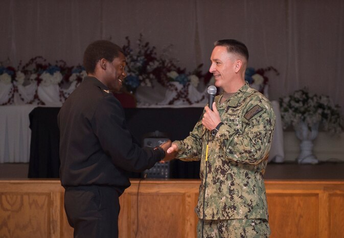 Petty Officer 3nd Class Labaron Johnson is coined by the Master Chief Petty Officer of the Navy, Mike Stevens, during an all hands event at the Joint Base Charleston – Weapons Station, S.C., March 24, 2016. Stevens was visiting the base as part of a two-week tour of East Coast military bases, from Norfolk, Virginia to Key West Fla.  Stevens wanted to communicate face-to-face with Sailors. (U.S. Air Force photo/Staff Sgt. Jared Trimarchi)