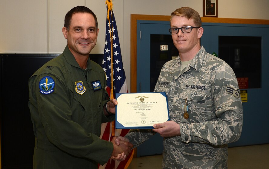 Col. Ethan Griffin, 62nd Airlift Wing vice commander, presents an Airman Medal to Senior Airman Joshua Calhoun, 62nd Maintenance Squadron precision measurement equipment laboratory journeyman, March 23, 2016 at Joint Base Lewis-McChord, Wash. Calhoun was recognized for his acts of heroism in April 2015 when he saved a surfer stranded on a rocky cliff after getting caught in a rip current at Ecola State Park in Oregon. (U.S. Air Force photo/Senior Airman Divine Cox)