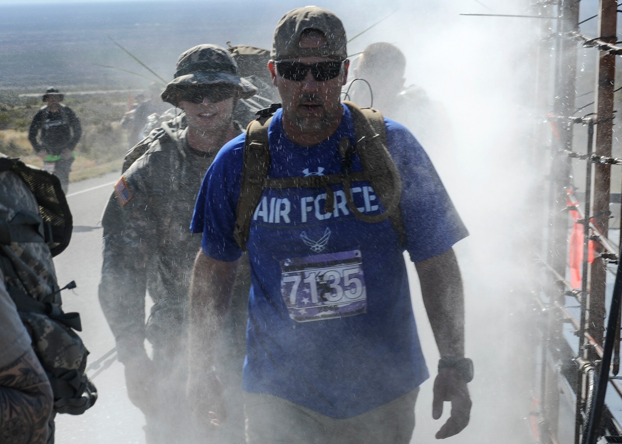 Kenneth Womack, 19th Logistics Readiness Squadron aerial delivery rigger supervisor, passes through a water mist machine along the 26.2 trek of the 2016 Bataan Death March at White Sands Missile Range, N.M., March 20, 2016. The march honors U.S. and Filipino prisoners of war during the notorious Bataan Death March of World War II. Historians estimate the death toll neared 10,000. (U.S. Air Force photo by Senior Airman Harry Brexel)