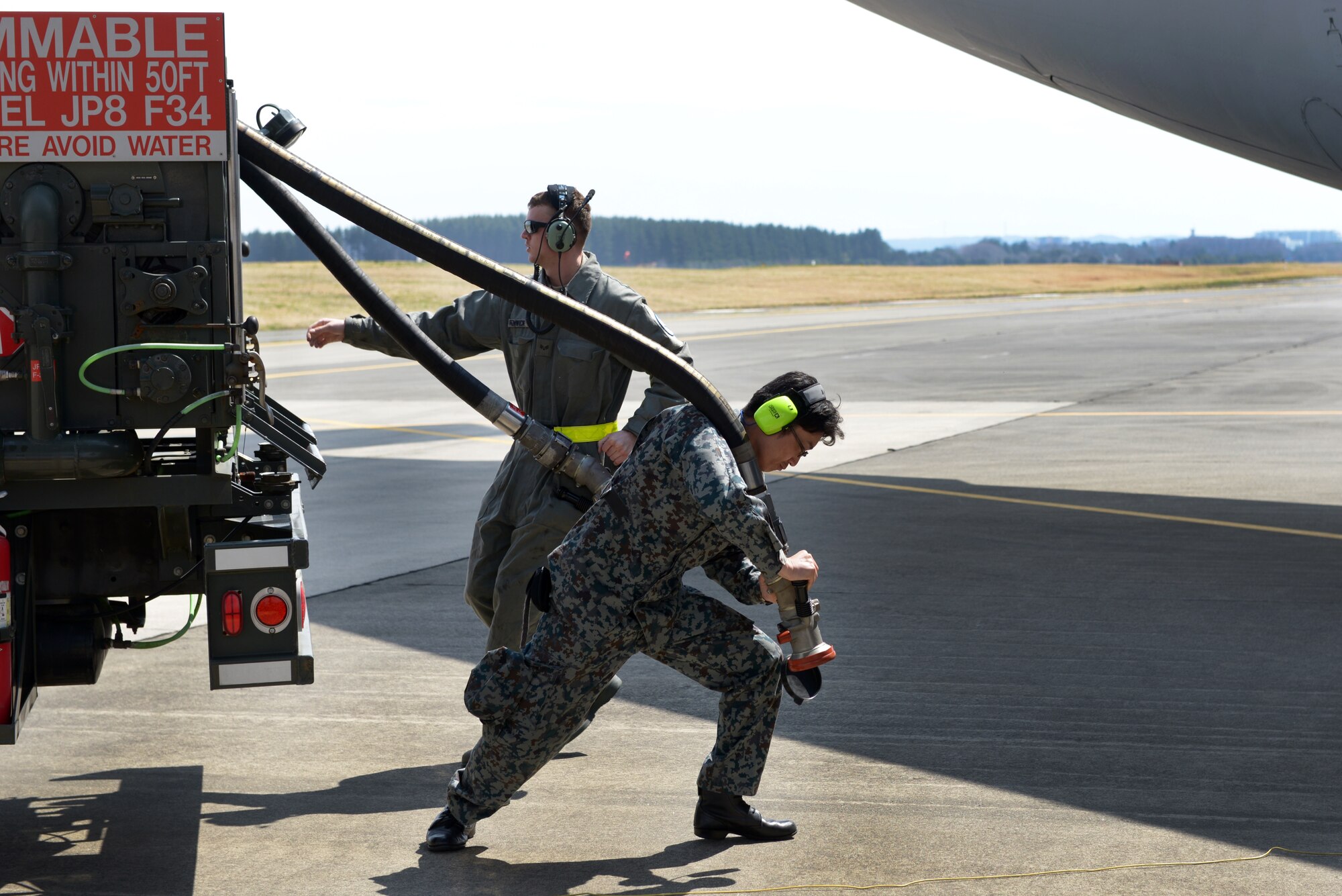Japan Air Self-Defense Force Staff Sgt. Keisuke Nishida pulls a fuel line toward a C-17 Globemaster during the 2016 Noncommissioned Officer Exchange Program at Yokota Air Base, Japan, March 21, 2016. The program offered JASDF members a chance to partner with Airmen and experience their working environment. (U.S. Air Force photo by Staff Sgt. Cody H. Ramirez/Released)