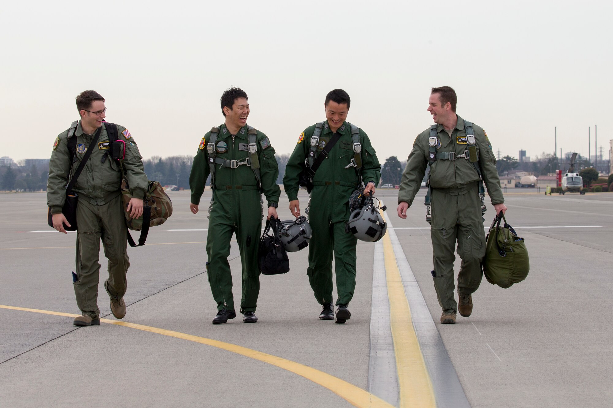 Loadmasters from Japan Air Self-Defense Force and U.S. Air Force walk on the flightline at Yokota Air Base, Japan, March 23, 2016, during the non-commission officer exchange program. Yokota hosted sixteen JASDF NCO members in various work-places for nine days. (U.S. Air Force photo by Osakabe Yasuo/Released) 