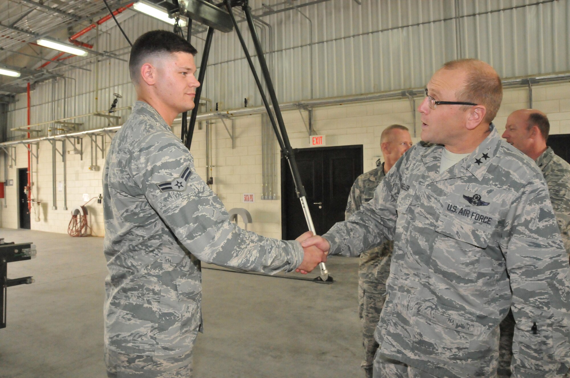 Maj. Gen. Andrew Mueller (right), Air Force Chief of Safety, coins Airman 1st Class William Link (left), 379th Expeditionary Maintenance  Squadron munitions systems specialist, during a visit to Al Udeid Air Base, Qatar March 16. Link won a safety award last month for his quick thinking that saved the lives of other airmen. (U.S. Air Force photo by Tech. Sgt. Terrica Y. Jones/Released)