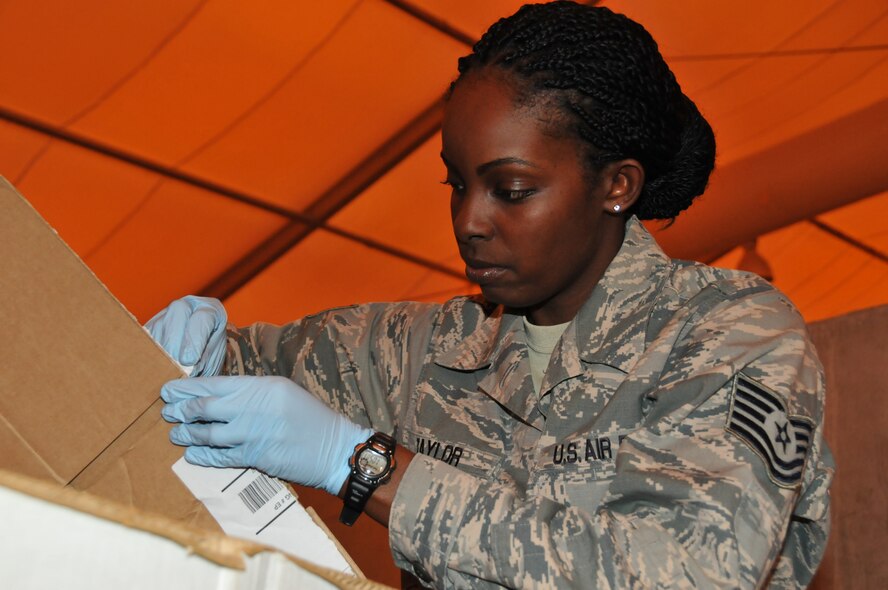 Tech. Sgt. Ashunta Taylor, 379th Air Expeditionary Wing operations security program manager takes labels off boxes at the shred tent March 15 at Al Udeid Air Base, Qatar. Taylor leads 47 operations security coordinators at AUAB. Taylor keeps track of OPSEC violations by working closely with force protection. (U.S. Air Force photo by Tech. Sgt. Terrica Y. Jones/Released)