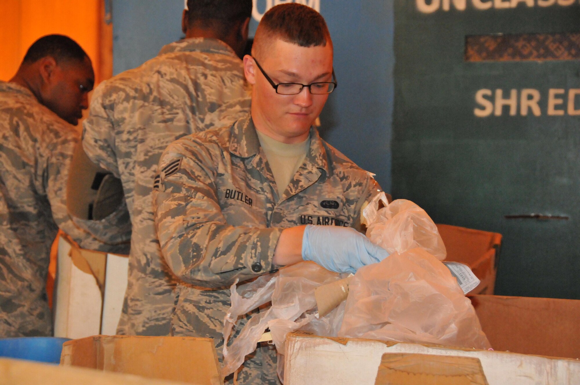 Senior Airman Devon Butler, 379th Expeditionary Civil Engineer Squadron force protection member, sort through bags of trash at the shred tent Mar. 15 at Al Udeid Air Base, Qatar. Bags of trash are sorted through for critical information, because personnel may have accidently thrown something away with it. (U.S. Air Force photo by Tech. Sgt. Terrica Y. Jones/Released)