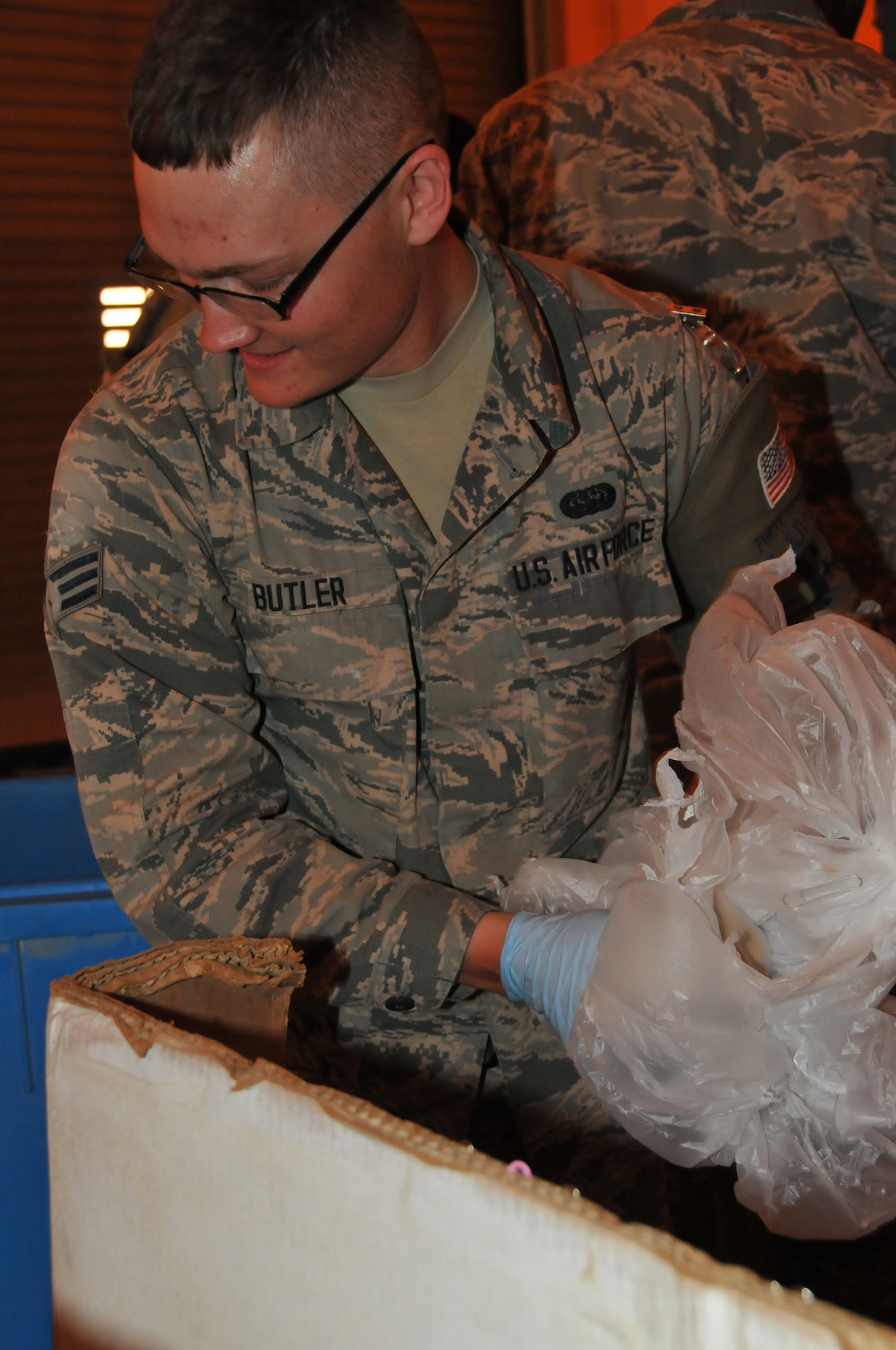 Airman Devon Butler, 379th Expeditionary Civil Engineer Squadron force protection member, sort through bags of trash at the shred tent Mar. 15 at Al Udeid Air Base, Qatar. Bags of trash are sorted through to prevent potential OPSEC violations. (U.S. Air Force photo by Tech. Sgt. Terrica Y. Jones/Released) 