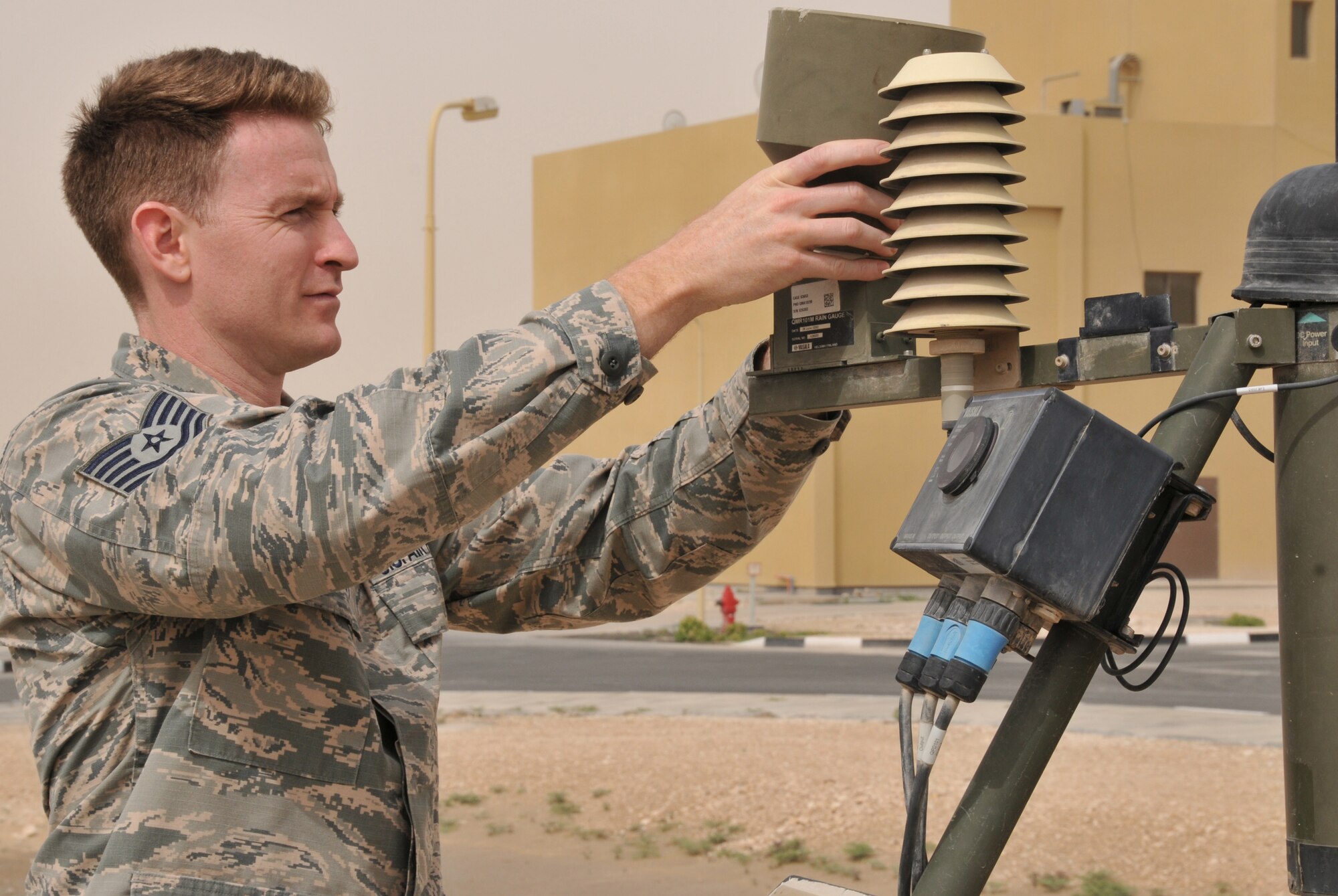 Tech. Sgt. Joshua Rowles, 379th Expeditionary Operations Support Squadron weather forecaster, checks a rain gauge March 17 at Al Udeid Air Base, Qatar. Rowles checks the gauge for bird’s nest which makes the Tactical Meteorological Observing System give false information. Rain gauges measure precipitation over a period of time. (U.S. Air Force photo by Tech. Sgt. Terrica Y. Jones/Released)