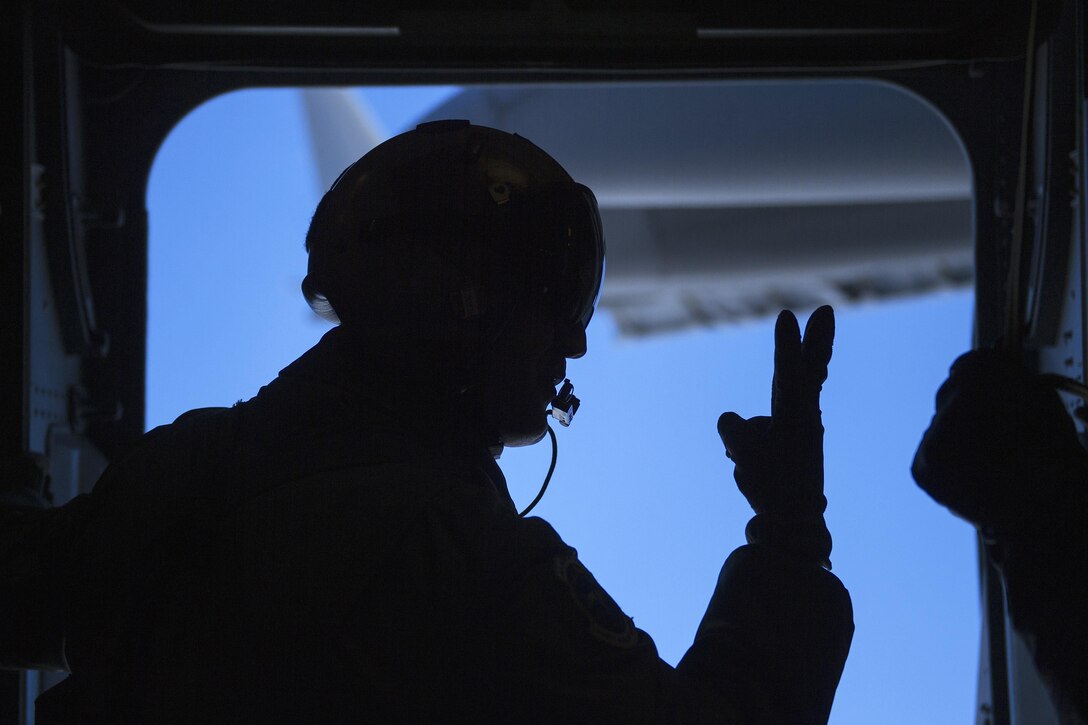 An airman uses hand signals and shouts commands before jumping out of a C-17 Globemaster III aircraft over Ice Camp Sargo to support Ice Exercise 2016 in the Arctic Circle, March 15, 2016. Air Force photo by Senior Airman James Richardson