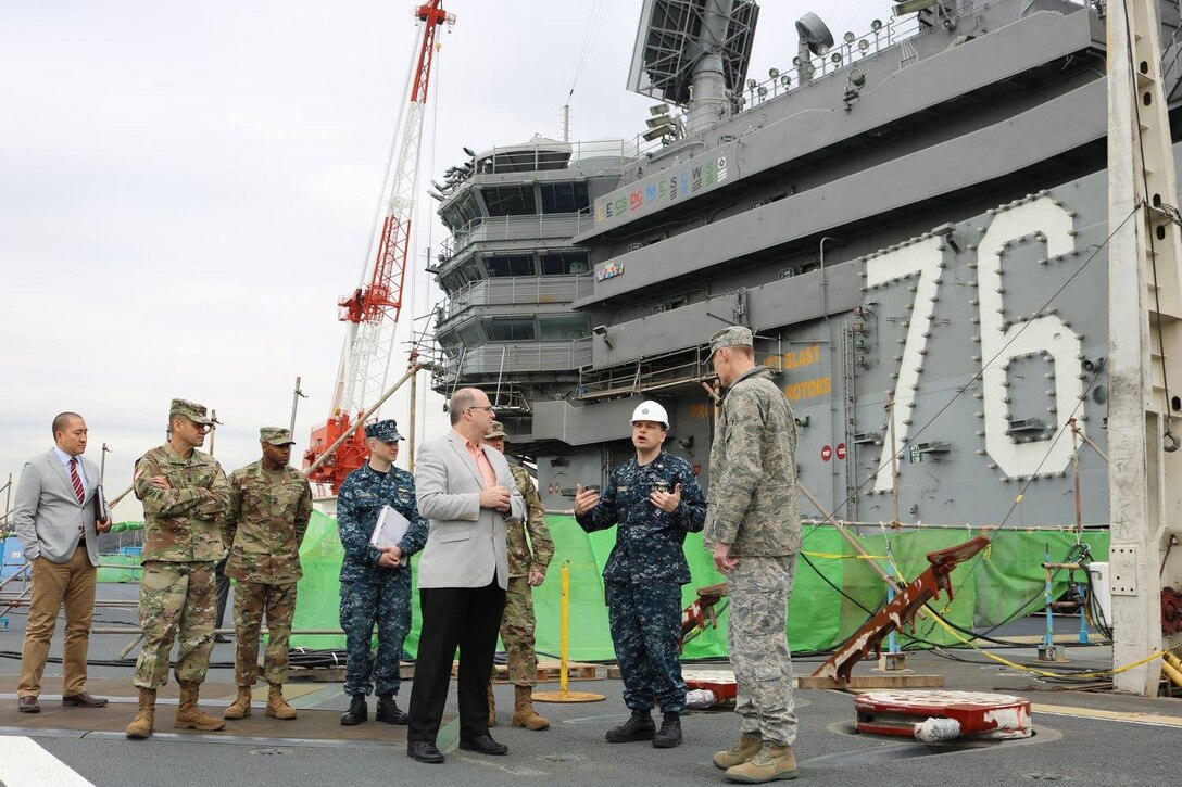 Busch and Jeff Curtis, executive director of support policy and strategic programs for DLA Logistics Operations, receive an overview of the USS Ronald Reagan by Navy Capt. Brian Anderson, before touring the ship in Yokosuka, Japan, March 16, 2016.