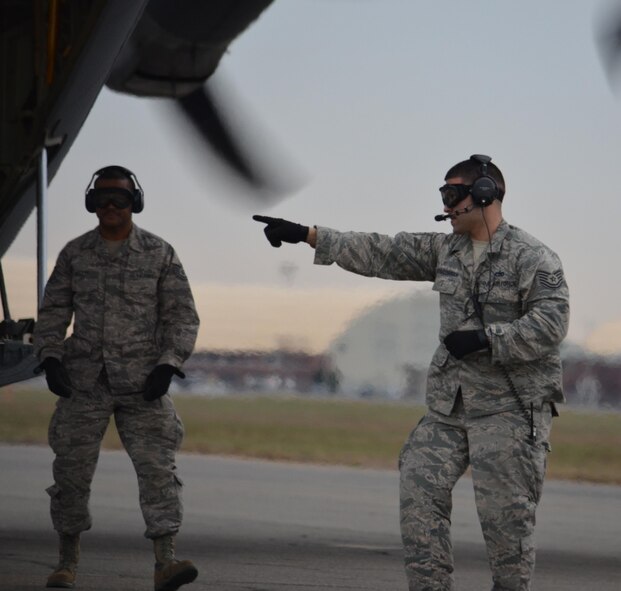 TSgt. Peter Alicia-Correa, 42nd Aerial Port Squadron, directs the onloading of munitions pallets onto a C-130J Super Hercules near Westover's Dogpatch training area, March 23.