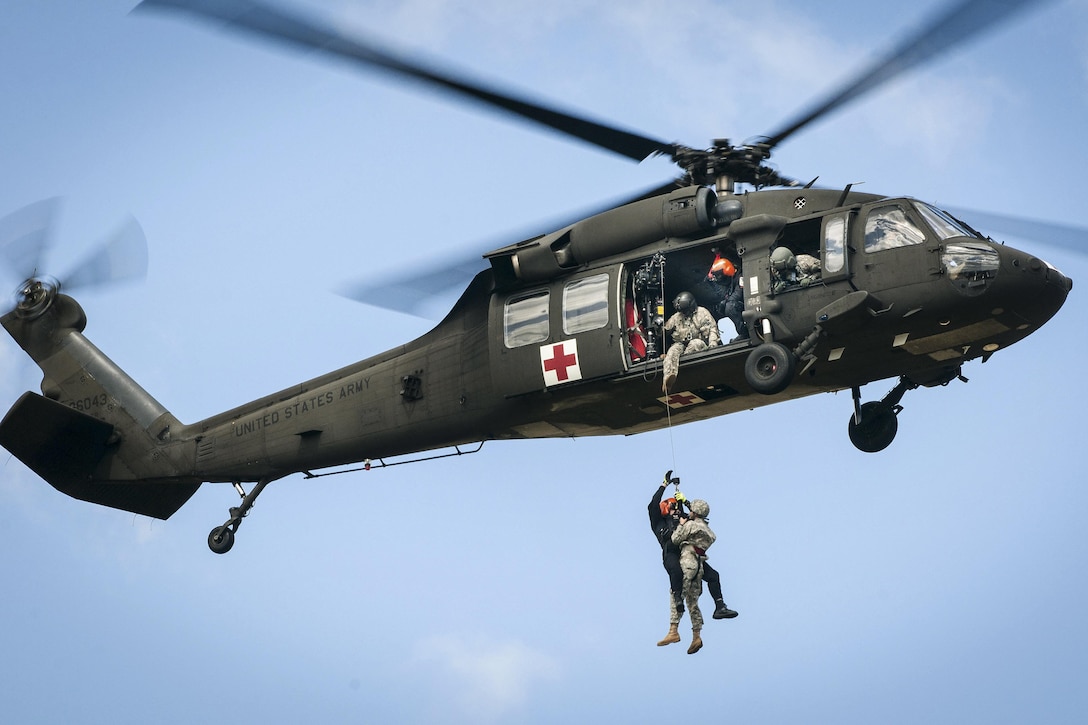 A soldier helps hoist a member of the South Carolina Helicopter Aquatic Rescue Team into a UH-60 Black Hawk helicopter during a medevac training and certification mission in Eastover, S.C., March 9, 2016. South Carolina Army National Guard photo by Staff Sgt. Roberto Di Giovine