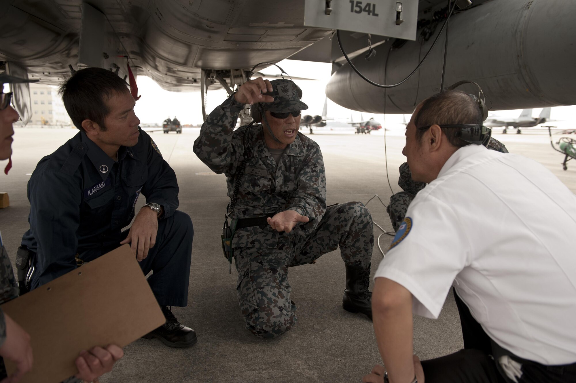Japan Air Self-Defense Force Master Sgt. Seiji Iwamoto, 9th Wing flight line boss, U.S. Air Force Koichiro Arakaki, 18th Civil Engineer Squadron firefighter, and Mitsuo Yamaguchi, 18th CES fire training officer, discuss protocols for handing fire emergency situations March 15, 2016, at Naha Air Base, Japan. JASDF aircrews and 18th CES Firefighters conducted fire training to enhance interoperability in the event of inflight emergencies. (U.S. Air Force photo by Senior Airman Peter Reft)