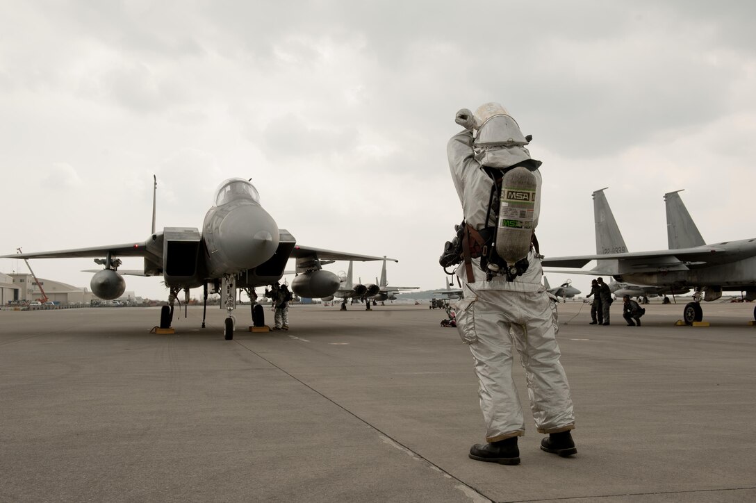 U.S. Air Force Senior Airman Patrick Walsh, 18th Civil Engineer Squadron firefighter, conducts aircraft barrier recovery training with a Japan Air Self-Defense Force F-15 Eagle fighter pilot assigned to the 9th Wing March 15, 2016, at Naha Air Base, Japan. USAF and JASDF partners overcame their language barriers by communicating through universal hand signals in compliance with North Atlantic Treaty Organization standardizations. (U.S. Air Force photo by Senior Airman Peter Reft)