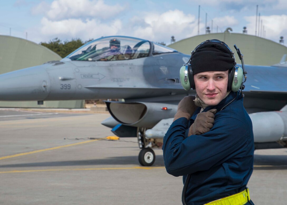 U.S. Air Force Airman Joseph Farmer, a crew chief with the 35th Maintenance Squadron, checks his surroundings before marshalling Lt. Col. Paul Miller, the deputy commander of the 35th Operations Group, to taxi down the runway during exercise Beverly Sunrise 16-03 at Misawa Air Base, Japan, March 23, 2016. Because of limited visibility in the cockpit, marshalling occurs before flight so crew chiefs can signal pilots onto the runway safely. (U.S. Air Force photo by Airman 1st Class Jordyn Fetter)