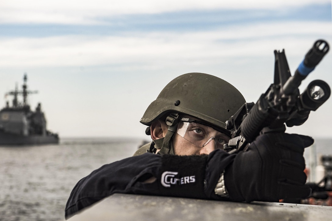 A sailor provides forward cover during a training exercise in the Atlantic Ocean, March 17, 2016. The sailor is a member of the visit, board, search and seizure team aboard the USS San Jacinto. The guided-missile cruiser is conducting the exercise with the Dwight D. Eisenhower Carrier Strike Group to prepare for a future deployment. U.S. Navy photo by Petty Officer 3rd Ryan U. Kledzik